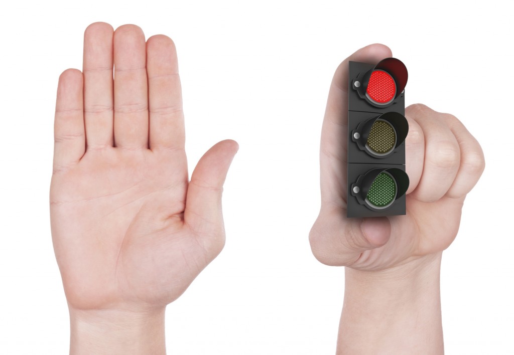 Concept denying access, hand holding traffic light. Isolated